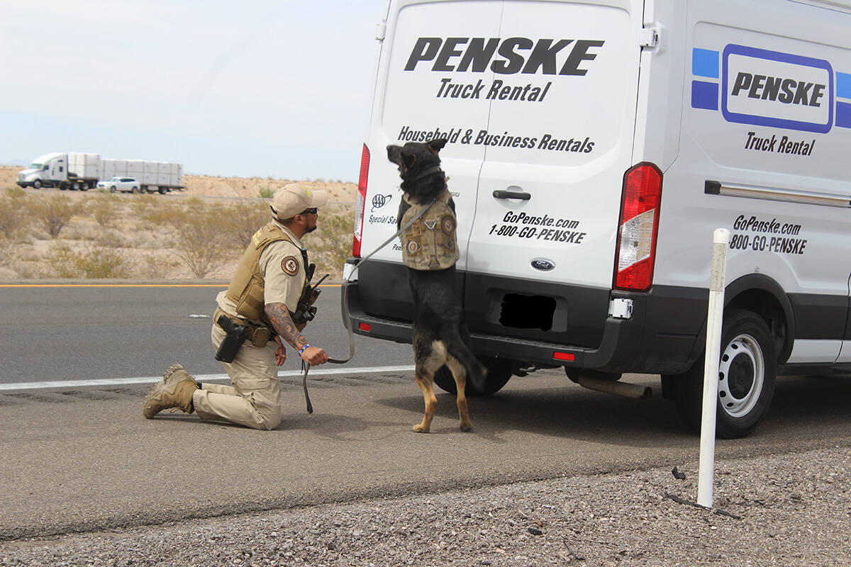 A Bureau of Indian Affairs K-9 officer and partner conduct an outside search of a rental truck ...