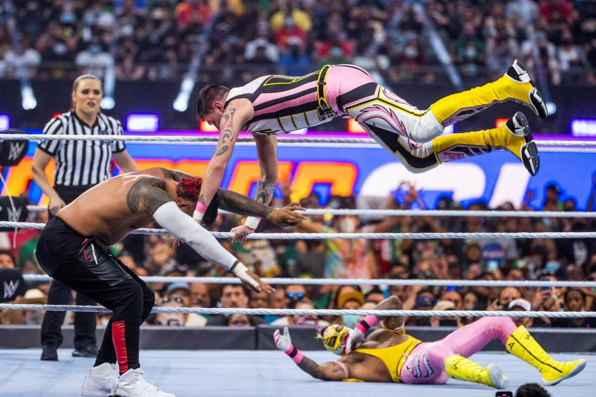 Jimmy Uso, left, has Rey Mysterio, top right, jump down on top of him with Dominik Mysterio bel ...