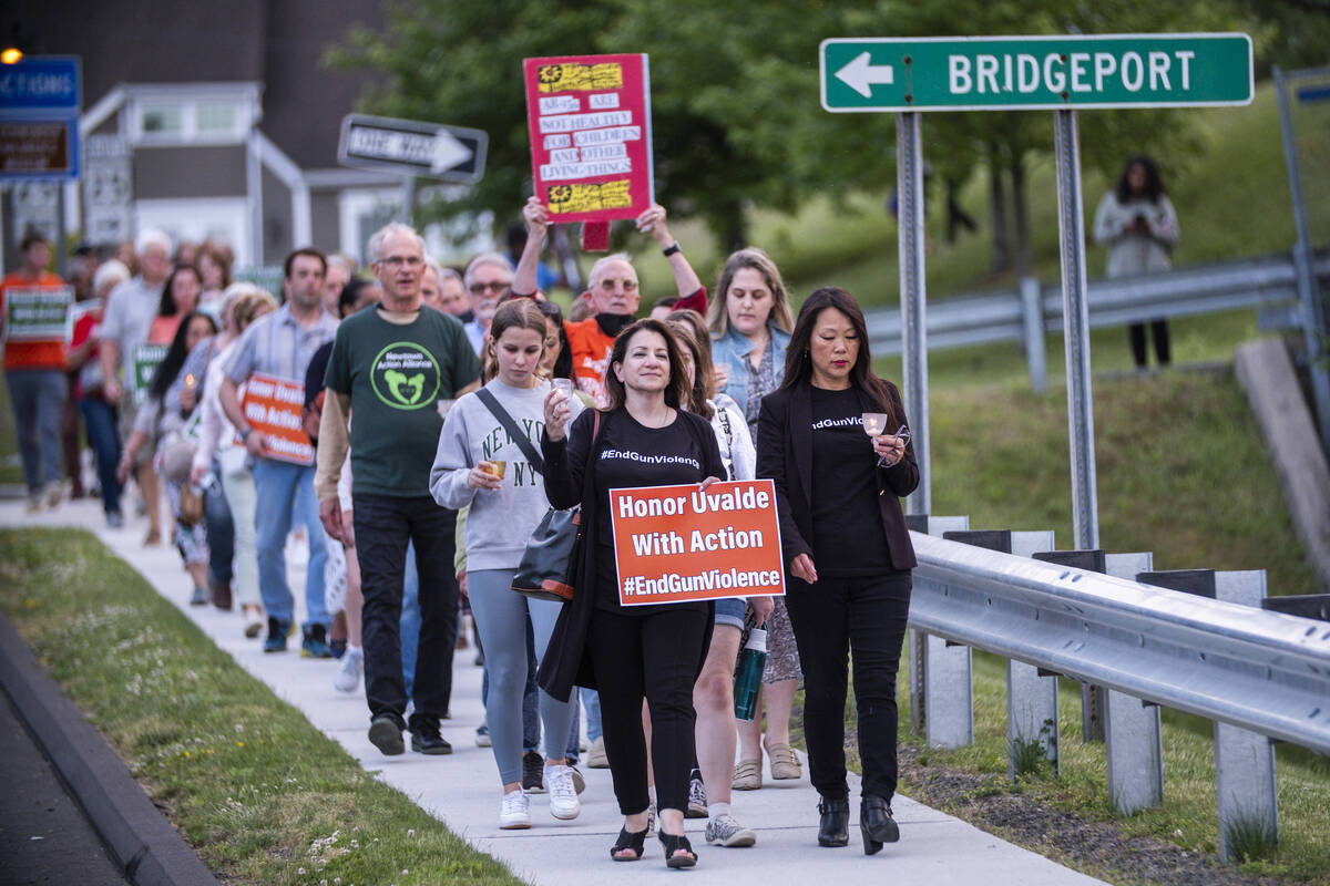 People march along a local street in Newtown, Conn., at the end of a vigil to stand in solidari ...