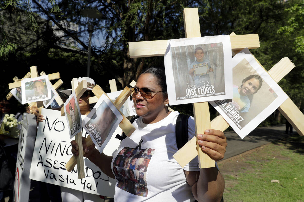 Nancy Pablo, with the Alianza Latina International, holds crosses with photos of victims of the ...