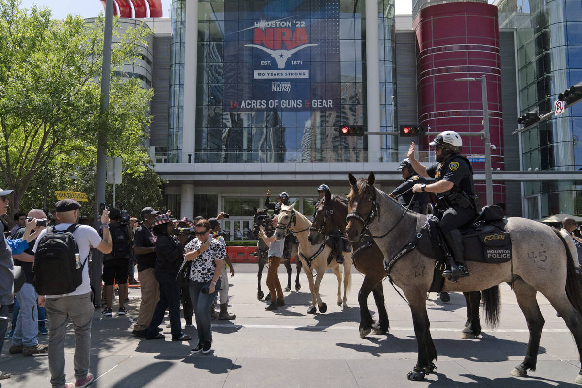 Mounted police officers tell protesters to move back across the street from the National Rifle ...