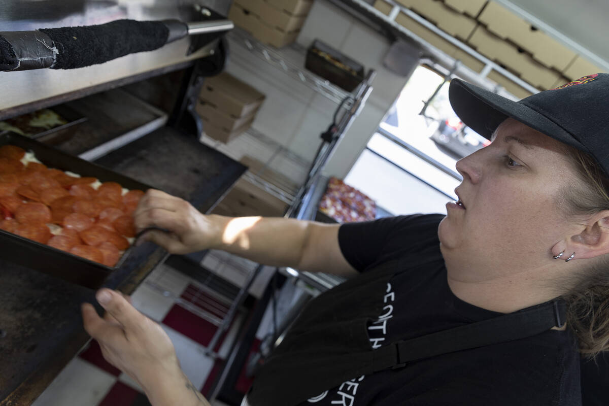 Cherish Geiger slides a Detroit-style pizza into the oven at Izzy’s Pizza Bus outside Ve ...