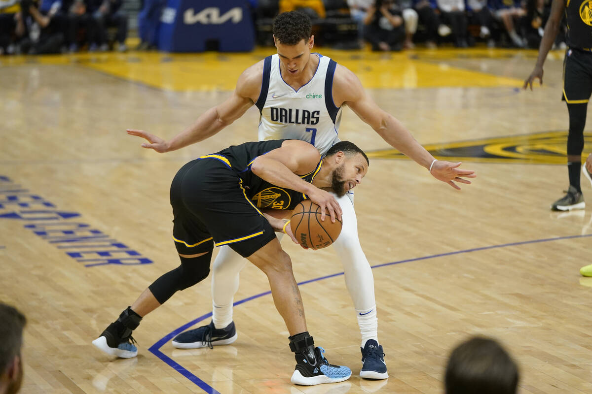 Golden State Warriors guard Stephen Curry, bottom, is defended by Dallas Mavericks center Dwigh ...