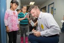 Chris Way of KTNV, Channel 13, helps a student during a United Way event at Hollingsworth Eleme ...