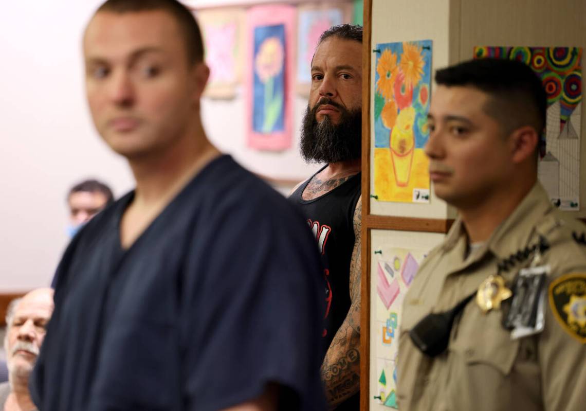 Stephen Alo, 46, left, hides behind a pillar during his initial court appearance in Henderson J ...