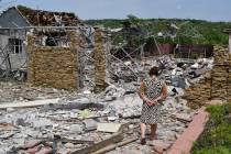 An elderly woman walks next to a building damaged by an overnight missile strike in Sloviansk, ...