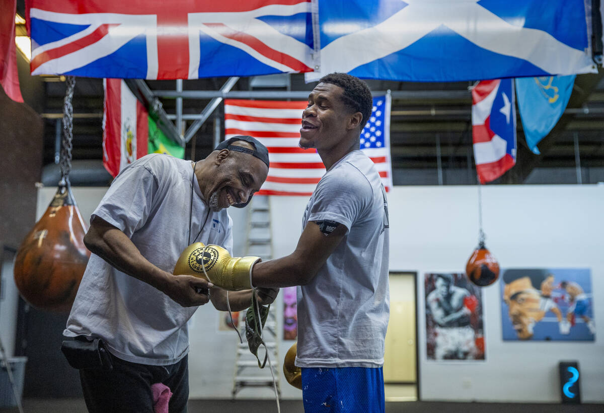 WBC lightweight boxer Devin Haney, right, is assisted with his gloves by trainer Darryl Flannig ...