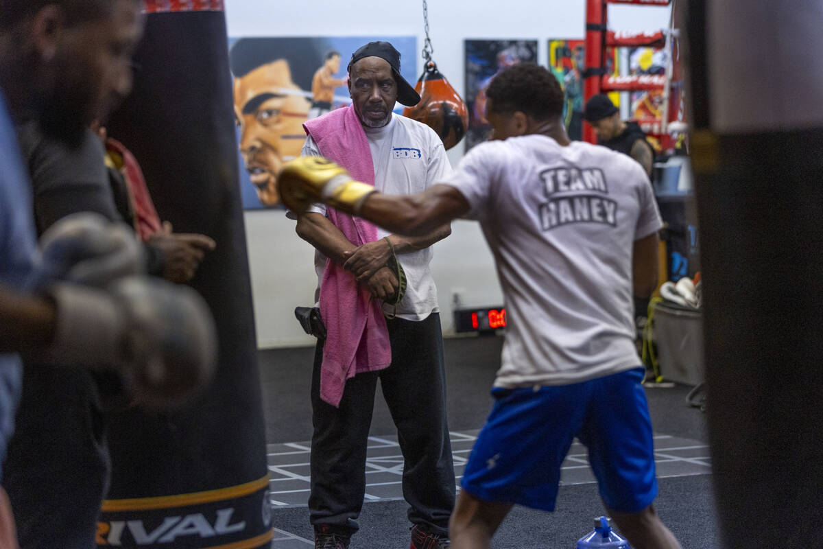 WBC lightweight boxer Devin Haney, right, throws a punch on a heavy bag as trainer Darryl Flann ...