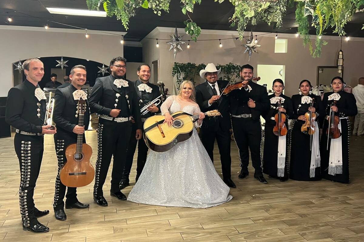 Newlyweds Mayra Ramos and Oscar Zuniga, in a white hat, pose with mariachis the day of their we ...