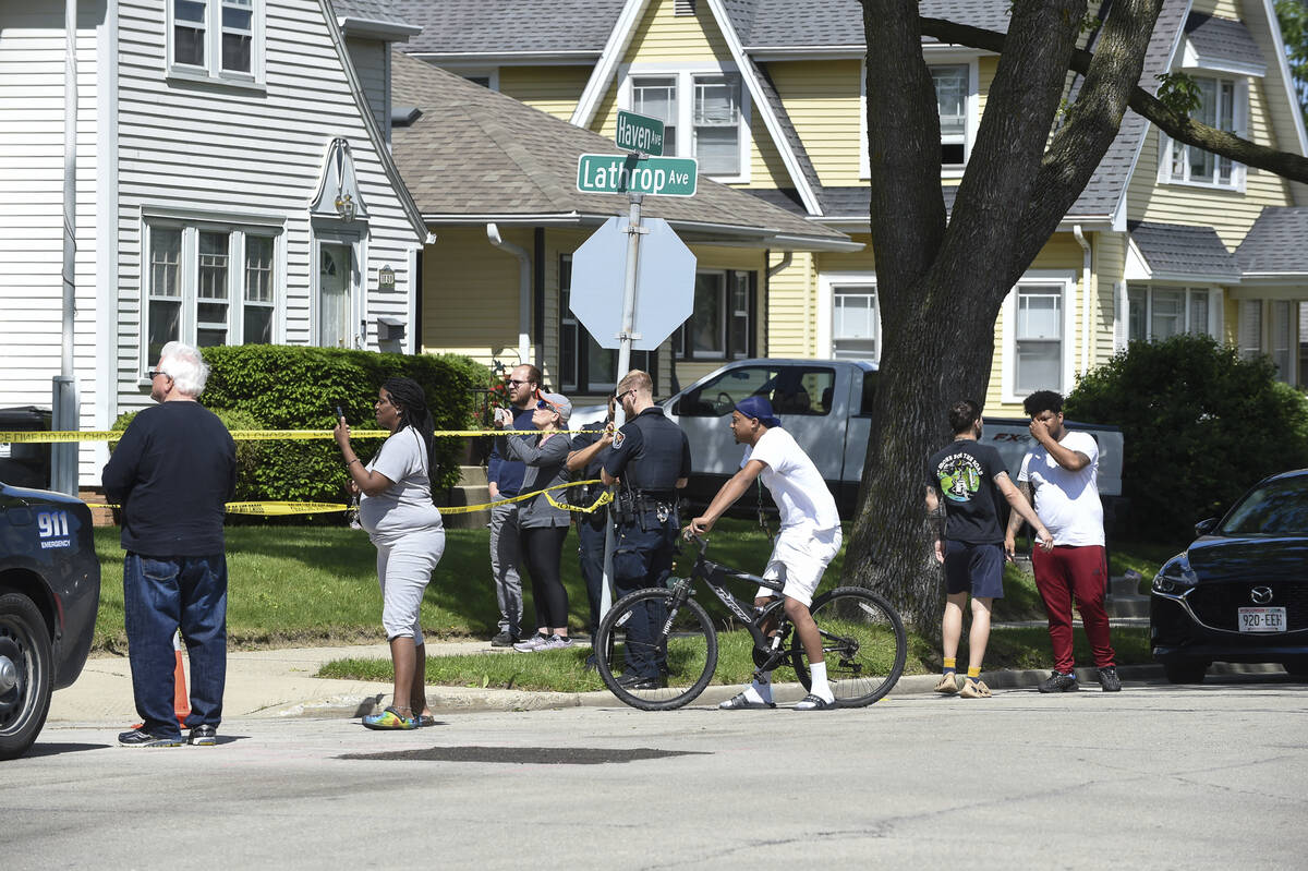 Law enforcement officers and onlookers fill the street outside Graceland Cemetery in Racine, Wi ...