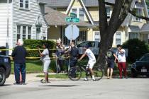 Law enforcement officers and onlookers fill the street outside Graceland Cemetery in Racine, Wi ...