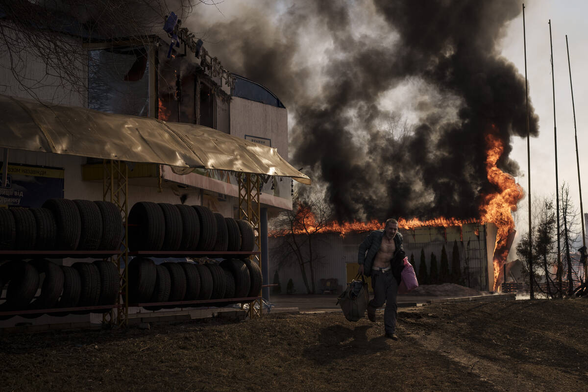 A man recovers items from a shop that caught fire from a Russian attack in Kharkiv, Ukraine, Fr ...