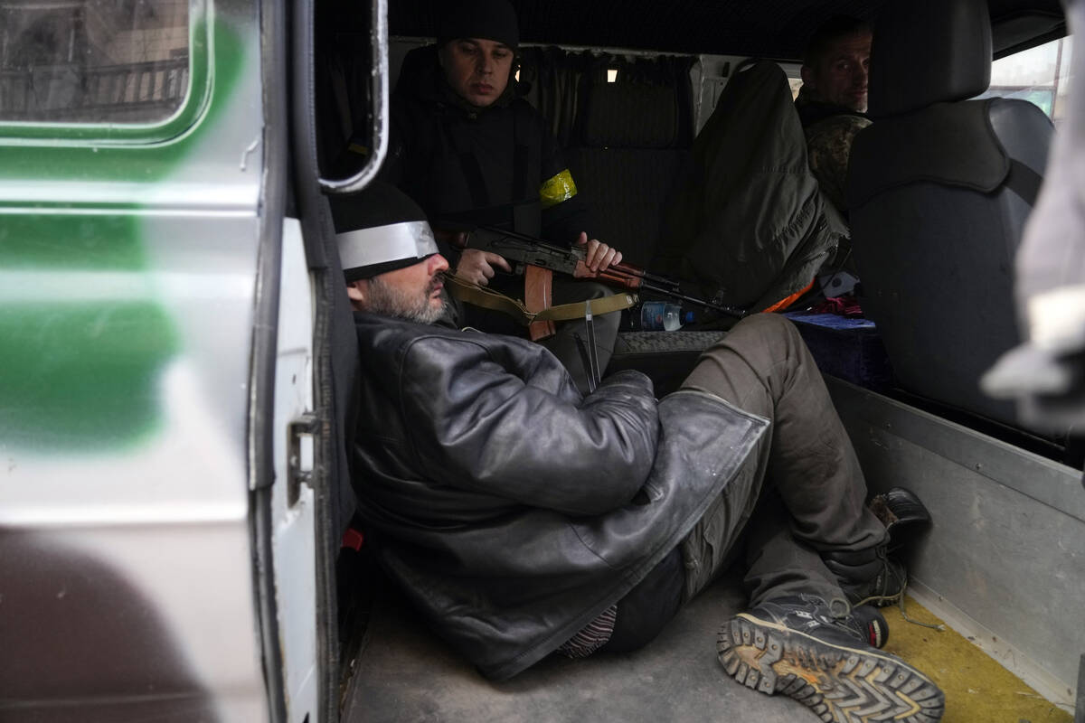 Ukrainian troops escort a suspected Russian agent in Kyiv, Ukraine, Sunday, Feb. 27, 2022. (AP ...