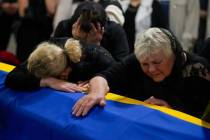 The mother, right, and sister of Army Col. Oleksander Makhachek mourn over the coffin with his ...