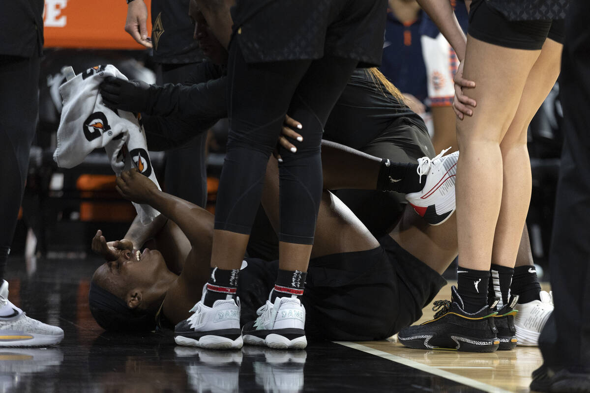 Las Vegas Aces guard Jackie Young (0) is surrounded by teammates and staff after getting injure ...