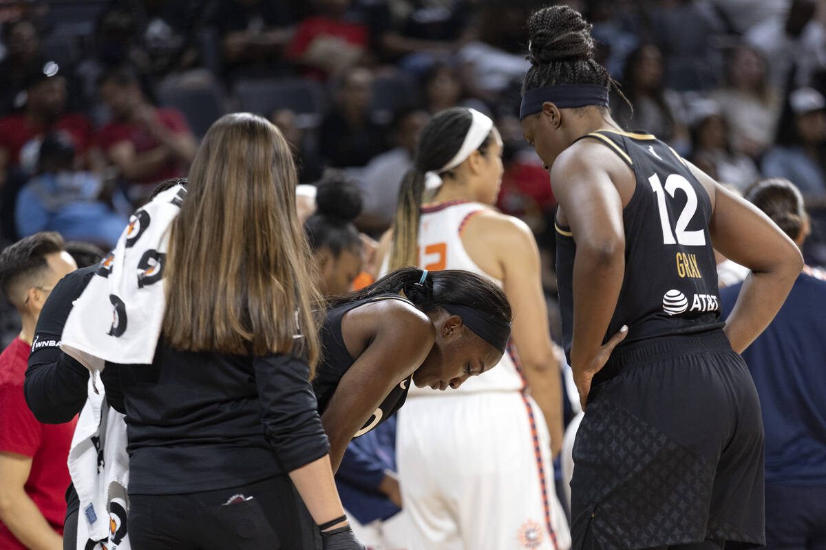 Las Vegas Aces guard Jackie Young, center, breathes through an injury before shooting her free ...