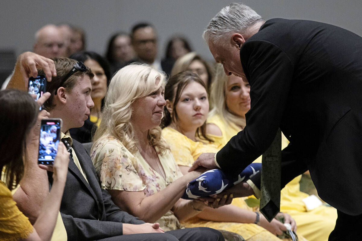 Jenn Closi, wife of Officer Phil Closi, accepts the flag from Gov. Steve Sisolak during her hus ...