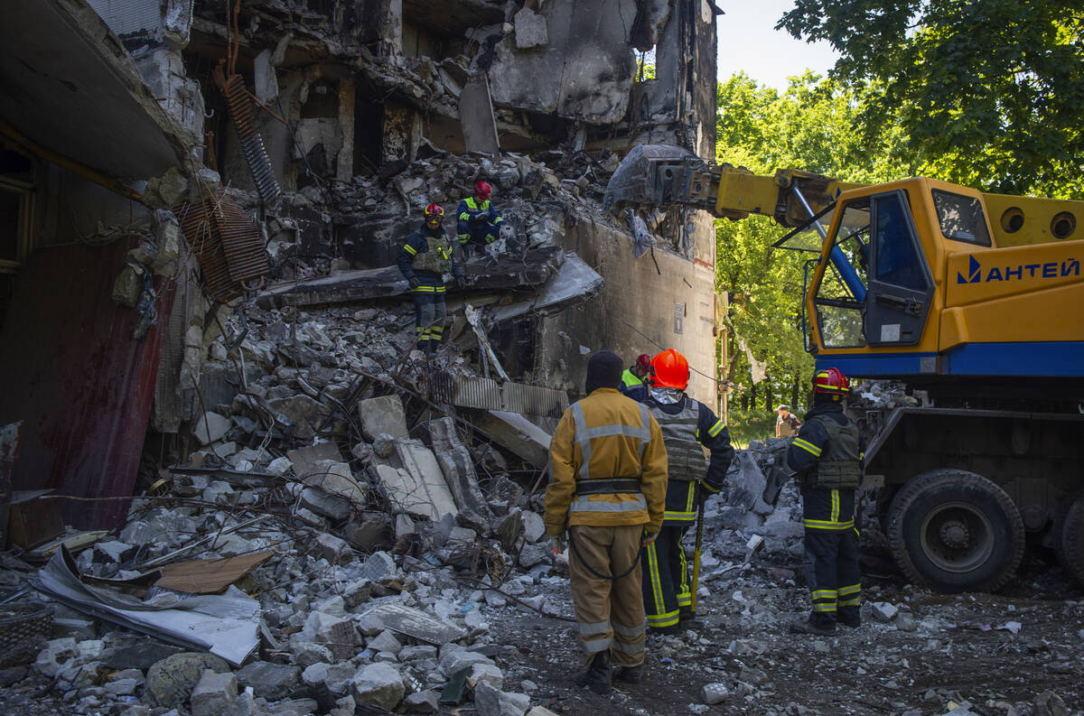 Ukrainian emergency service personnel work outside a damaged building following shelling, in Kh ...