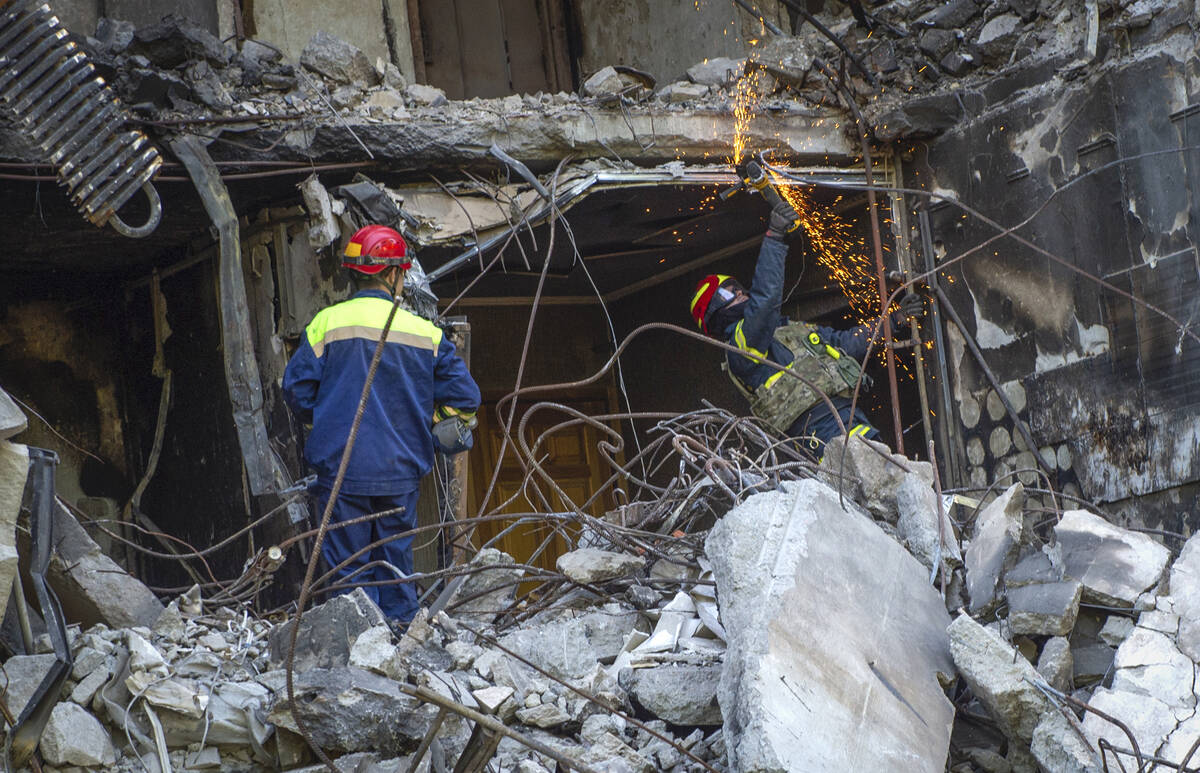Ukrainian emergency service personnel work outside the damaged building following shelling, in ...