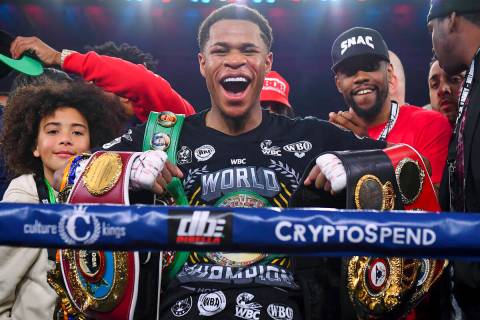 Devin Haney, center, of the United States, poses with his belts after defeating Australia's Geo ...
