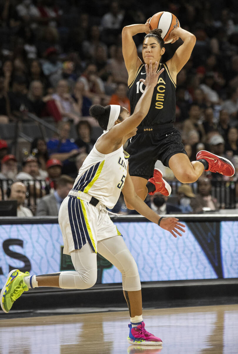 Aces guard Kelsey Plum (10) leaps over Dallas Wings guard Tyasha Harris (52) to make a pass in ...