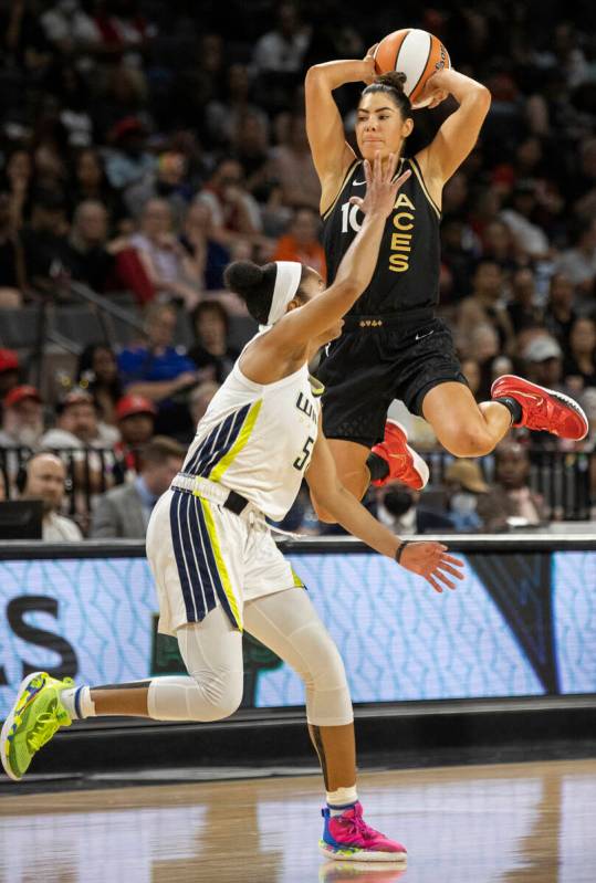 Aces guard Kelsey Plum (10) leaps over Dallas Wings guard Tyasha Harris (52) to make a pass in ...