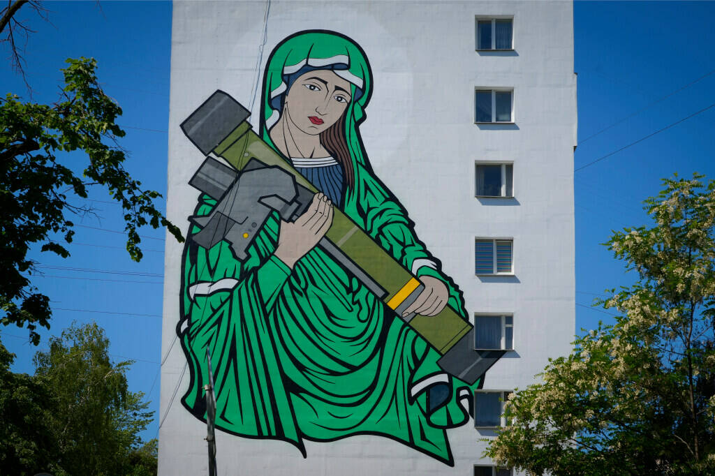 A mural depicts an image known as "Saint Javelina"- Virgin Mary cradling a US-made FGM-148 anti ...