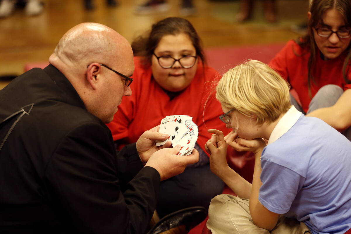 Kristlynn Allison, right, and Jensen Martin, center, watch as magician Adam London does a card ...