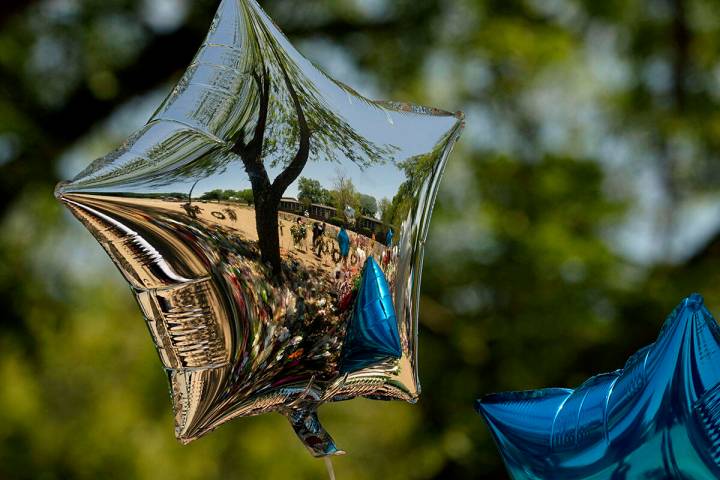 Mourners are reflected in a balloon at a memorial outside Robb Elementary School created to hon ...