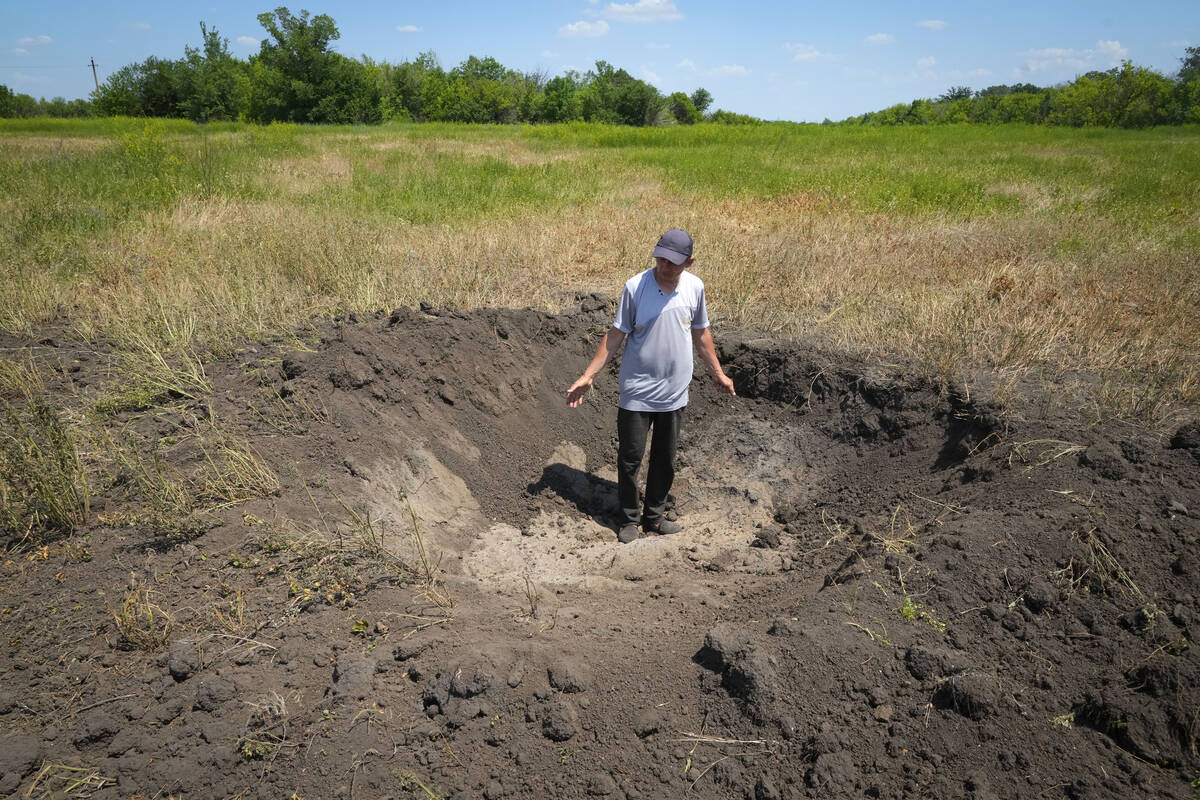 Farmer Serhiy, a local grain producer, shows a crater left by a Russian shell on his field in t ...