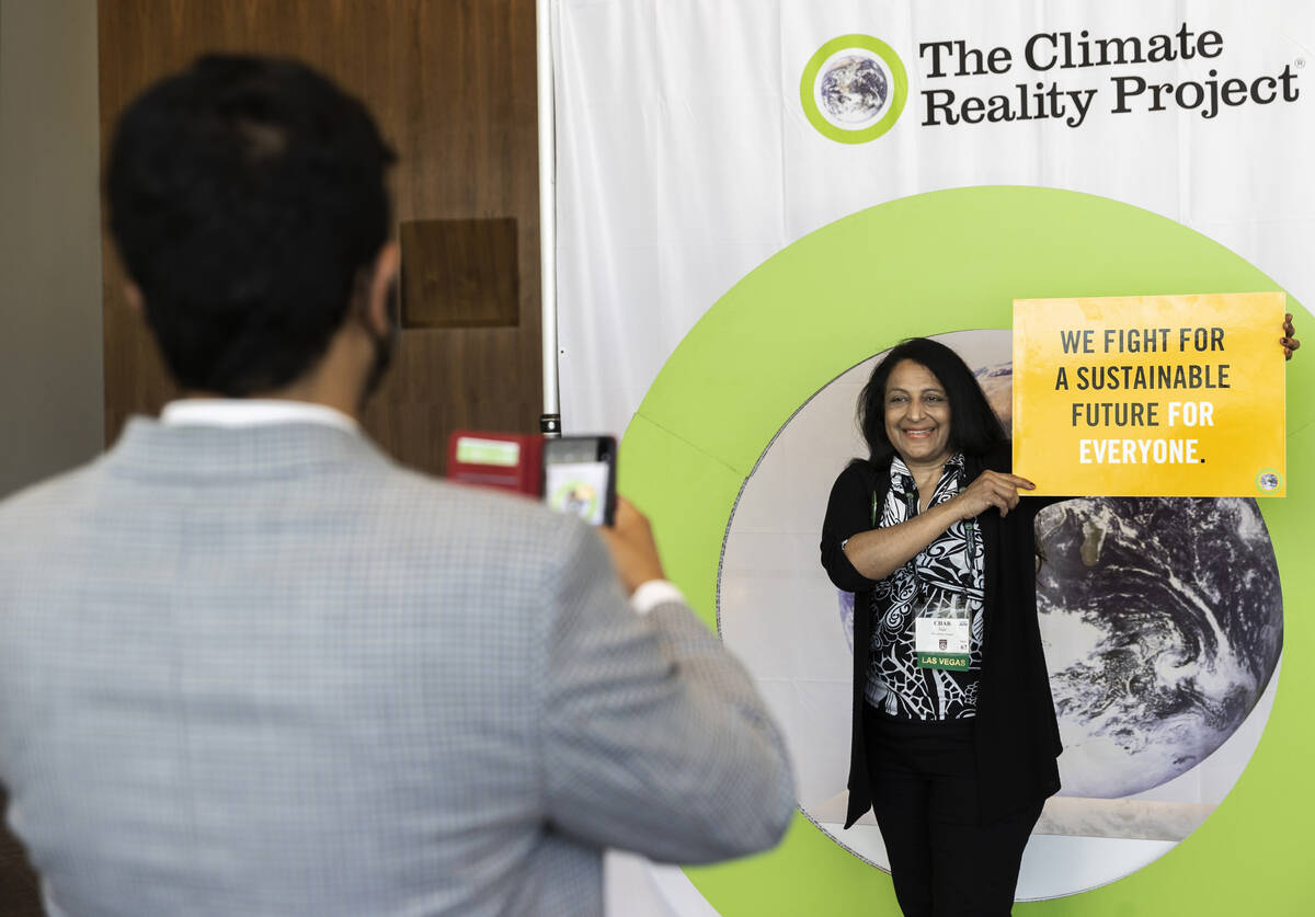 Charu Nair, right, from Marylhurst, Ore., takes a photo holding a sustainability sign at the Cl ...