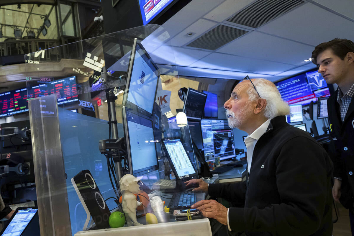 In this photo provided by the New York Stock Exchange, trader Peter Tuchman, seated, works on t ...