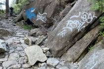 A hiker walks down a graffiti covered trail in Yosemite National Park, Calif., in June 2022. (N ...