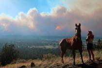 Janetta Kathleen and her horse, Squish, watch as smoke rises above neighborhoods on the outskir ...