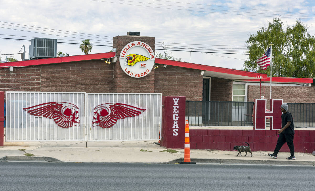 A pedestrian walks his dog past the exterior of the Hells Angels Motorcycle Club building along ...