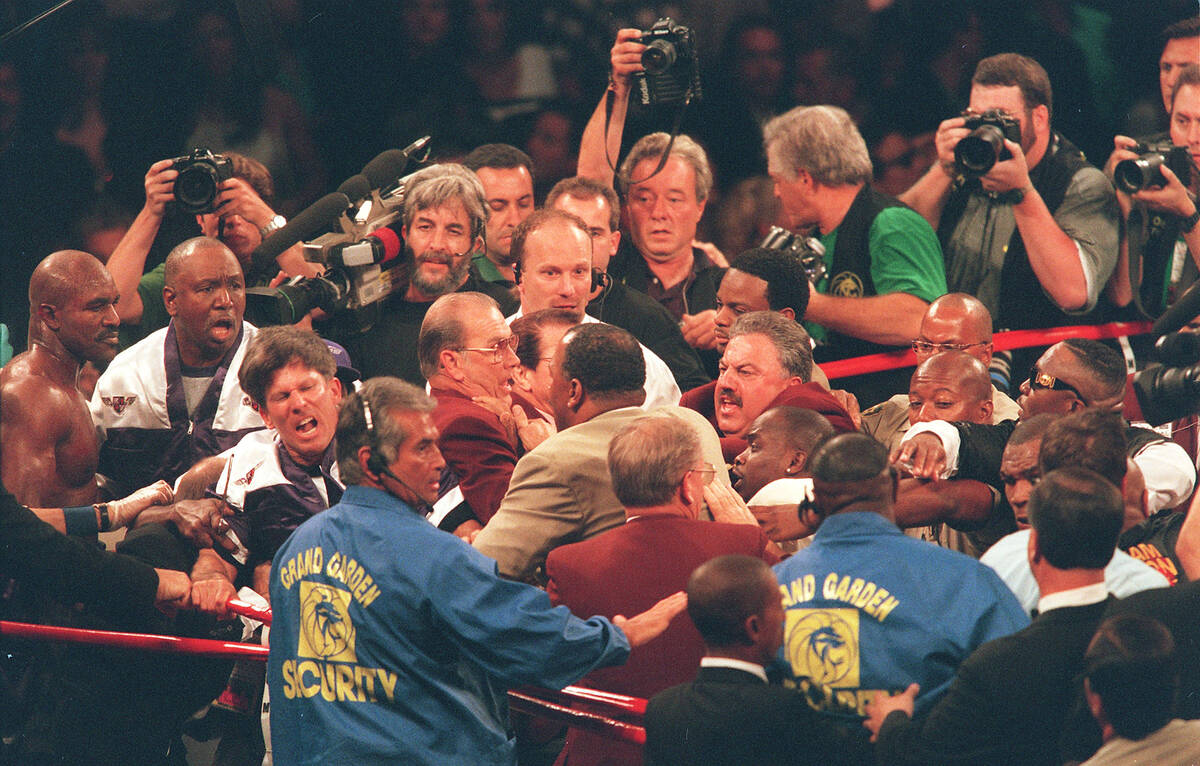 Evander Holyfield, far left, looks on as a melee breaks out following the stop of the fight bef ...