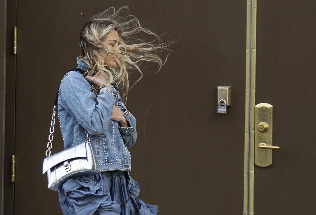 A pedestrian has her hair blown by strong wind as she walks along Main Street in downtown on Ma ...