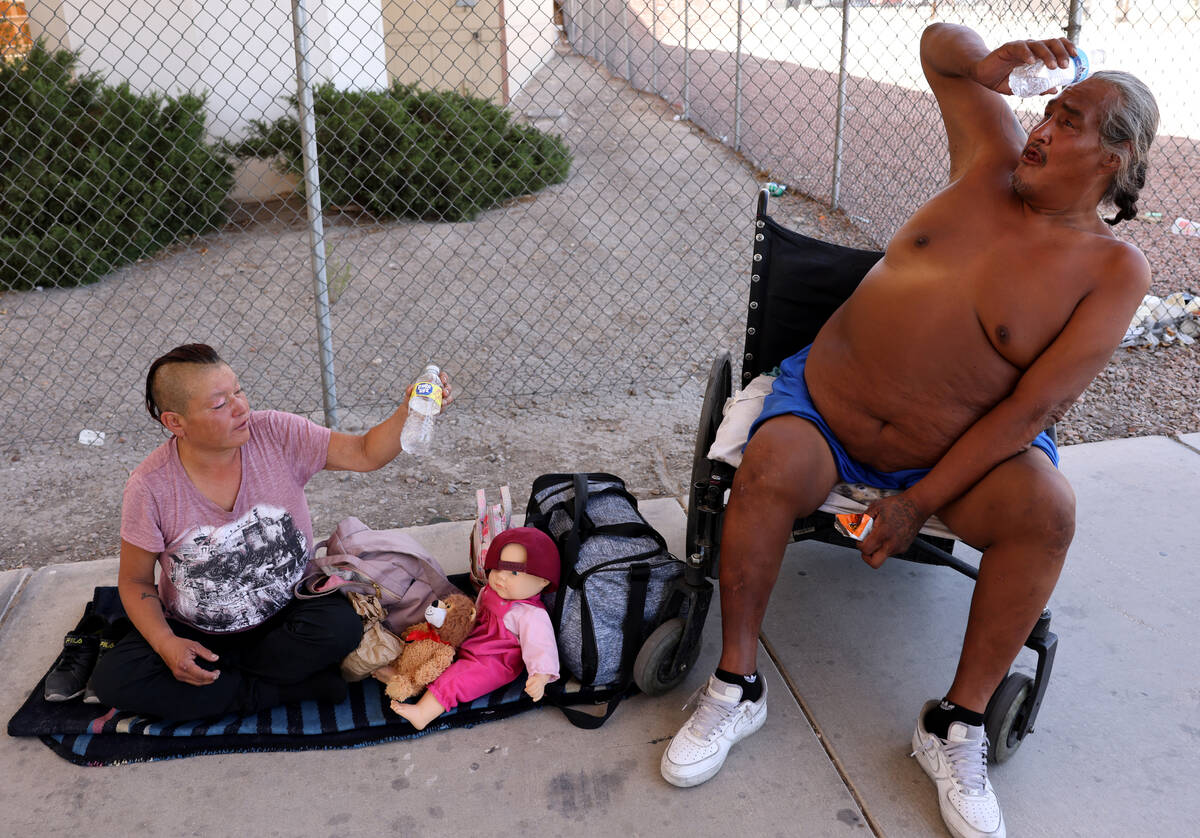 Denise Lopez and Tracy Alen Morrison douse themselves with water in the shade under U.S. Highwa ...