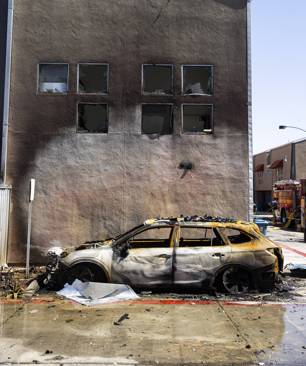 A burned-out vehicle is pictured at the scene where a fire damaged or destroyed at least 10 bui ...