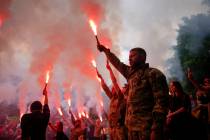 Soldiers hold flares as they attend the funeral of activist and soldier Roman Ratushnyi in Kyiv ...