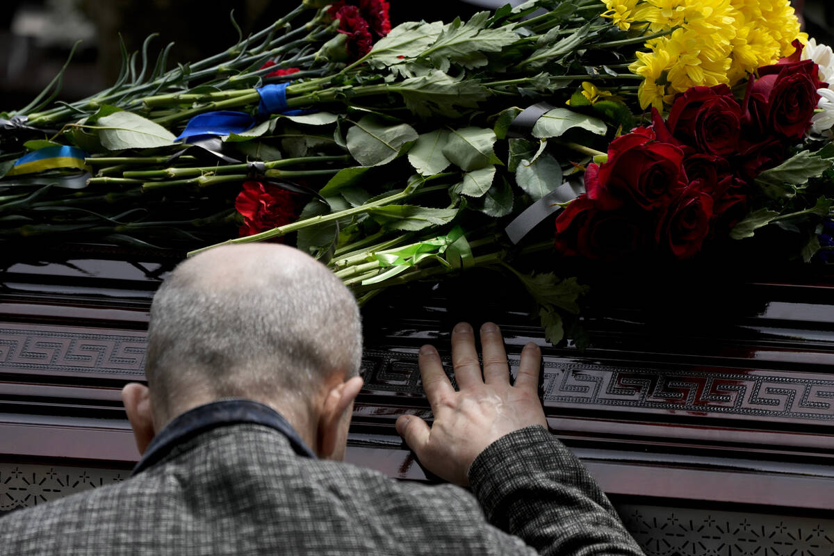A man touches the coffin with the remains of activist and soldier Roman Ratushnyi during his fu ...