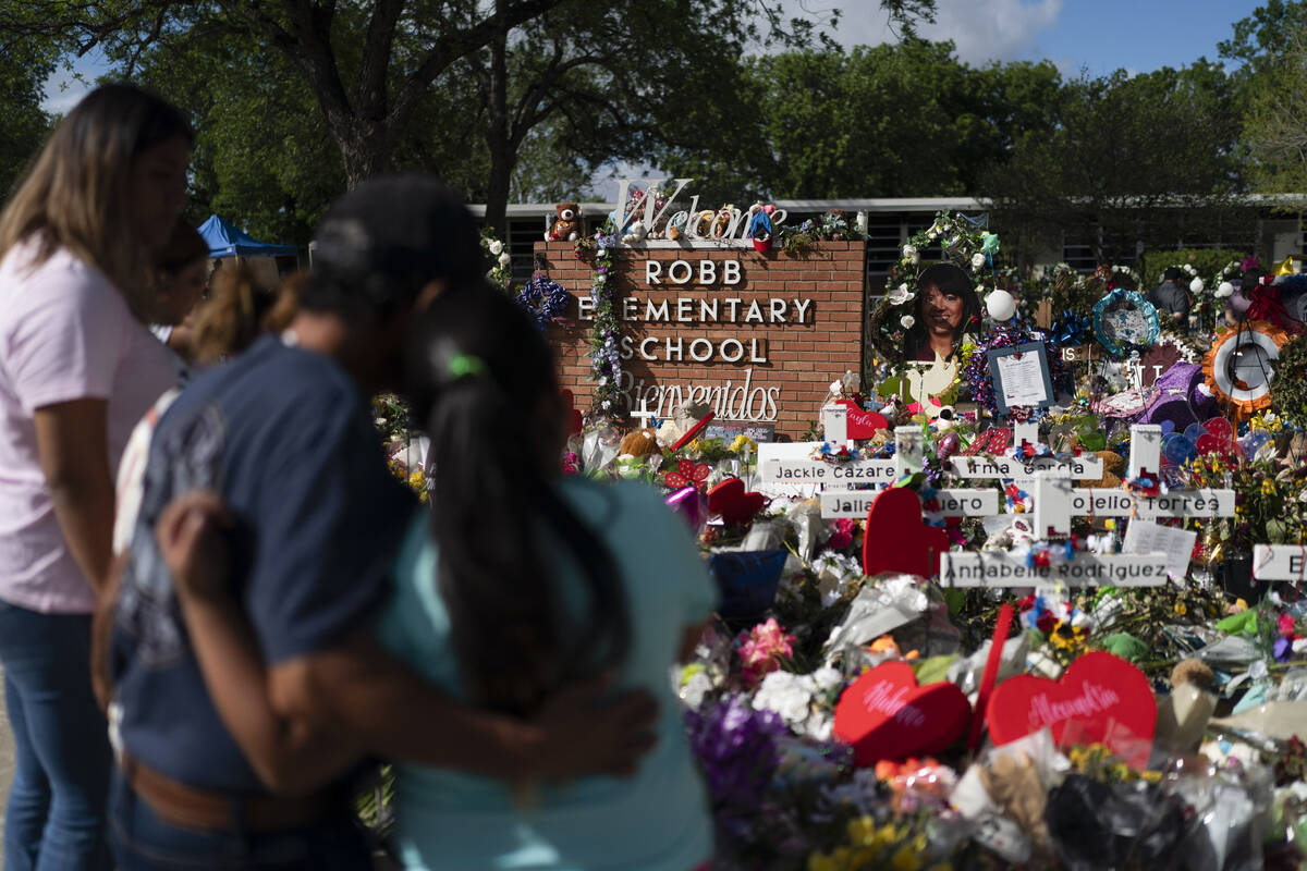 FILE - People visit a memorial at Robb Elementary School in Uvalde, Texas, on June 2, 2022, to ...