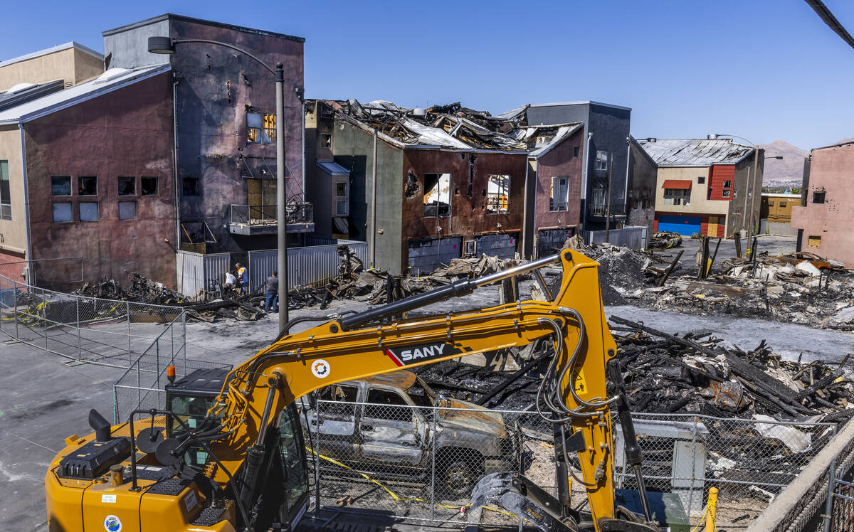 A crew works on a metal gate within the Urban Lofts Townhomes property where fire originated fr ...