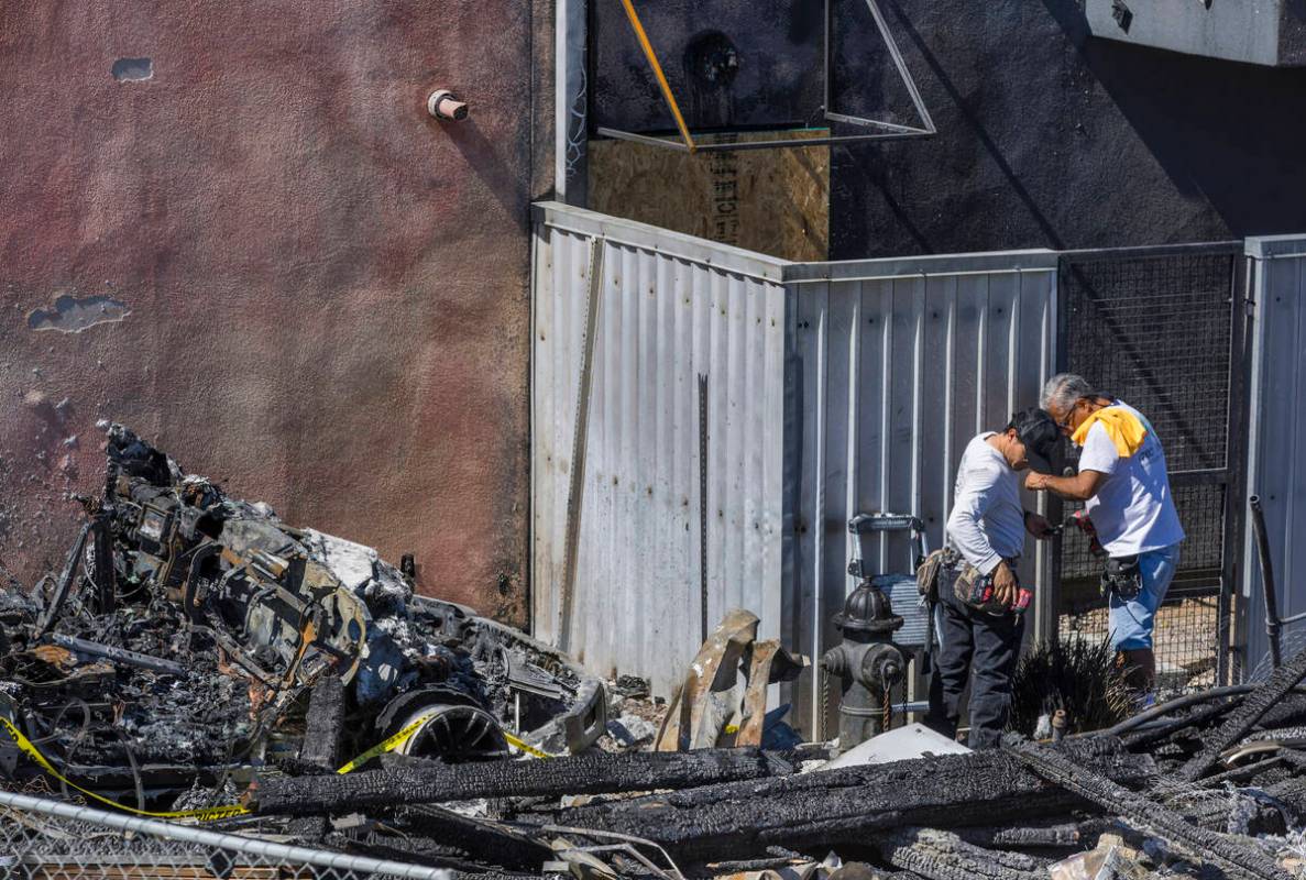 A crew works on a metal gate within the Urban Lofts Townhomes property where fire originated fr ...