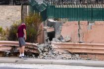 A pedestrian looks at a damaged wall after a fatal crash near the intersection of Charleston B ...