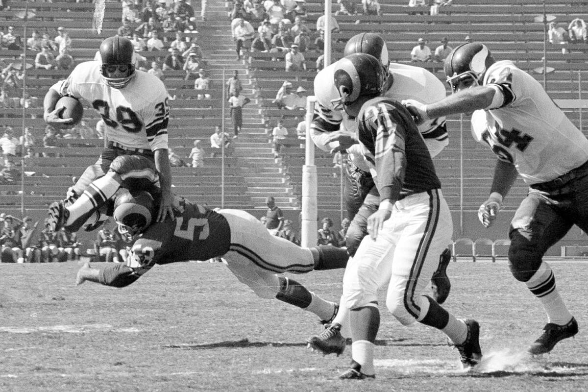 Minnesota Vikings halfback Hugh McElhenny, left, takes to the air to get past a Los Angeles Ram ...