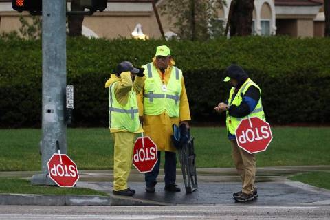 Crossing guards, wearing rain jackets, chat as they wait for students from Elise Wolff Elementa ...