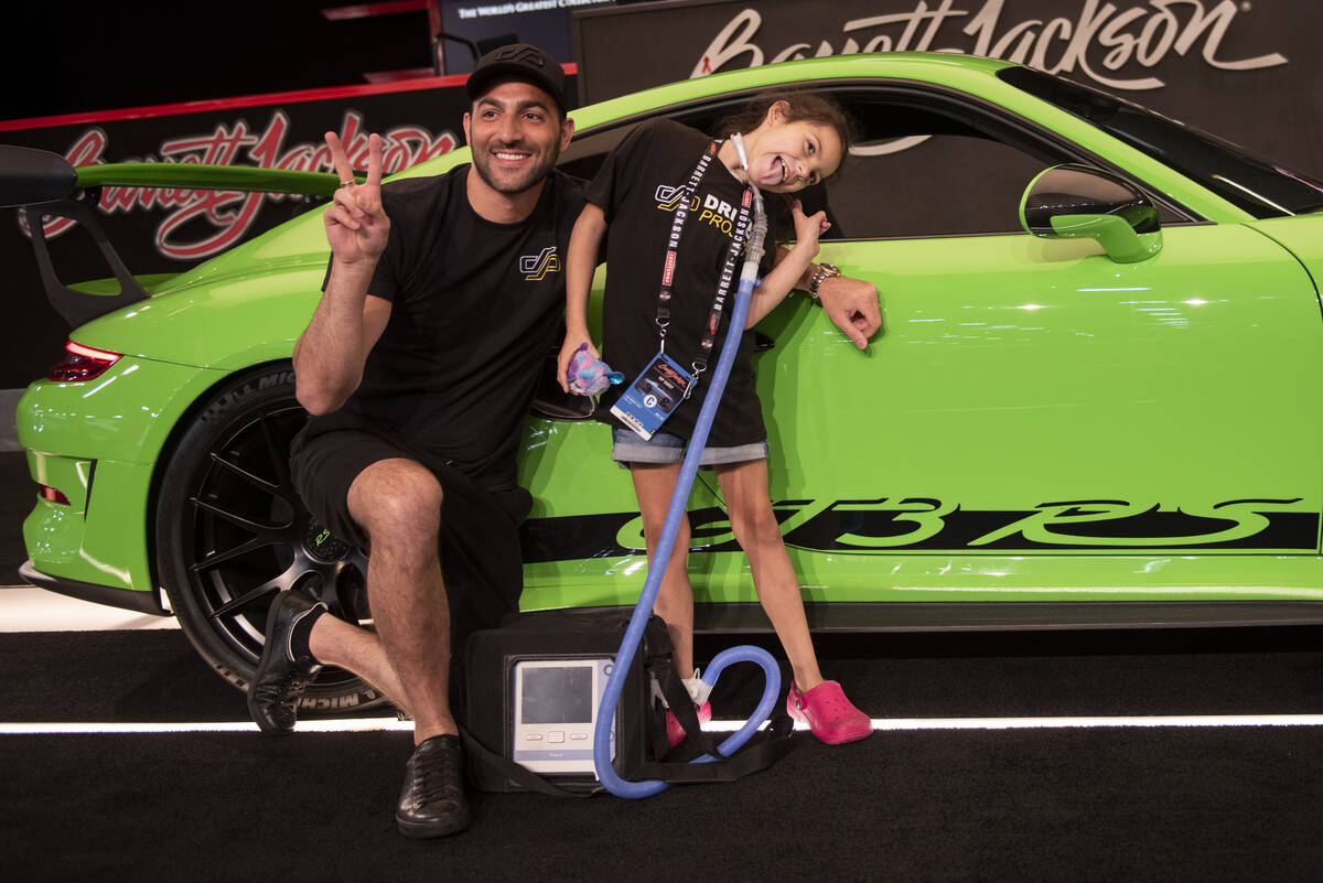 Adrianna Renteria, 8, goofs off while posing for photos in front of a Porsche GT3RS driven by R ...