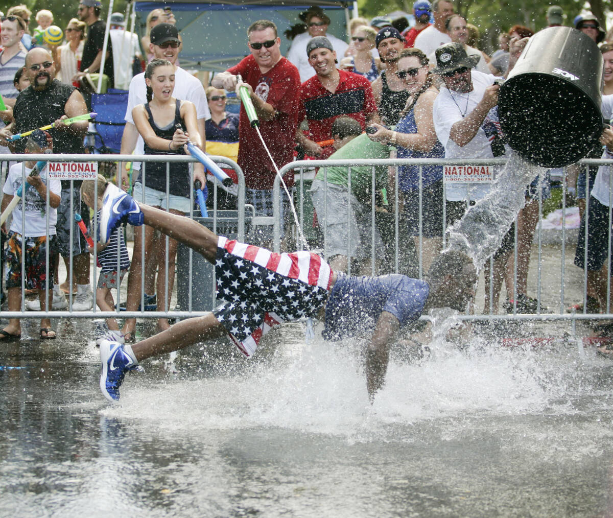 In this Thursday, July 4, 2013, file photo, Roger Johnson, center, is doused with water as he d ...