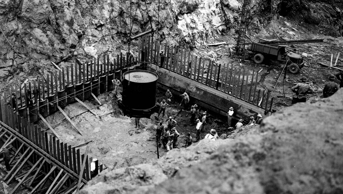 A steel bucket holding eight cubic yards dumps the first load of concrete for the foundation of ...